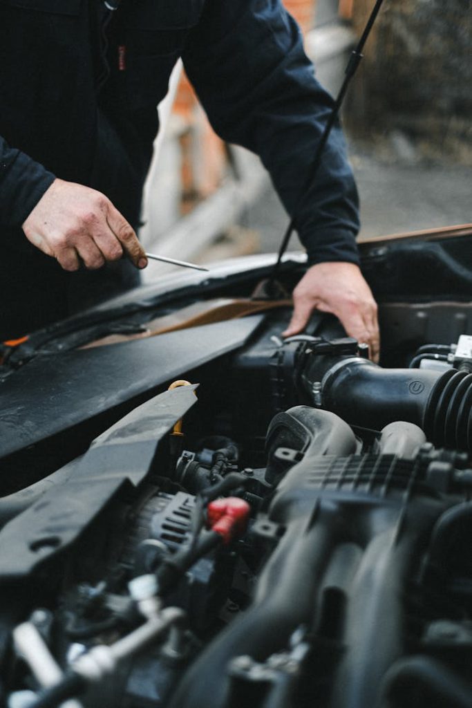 person-in-black-long-sleeves-repairing-the-car-engine-4315574 A mechanic working on a car engine with tools, focused on repairs.